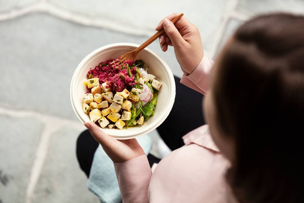 Woman eating salad in an office from a smart vending machine
